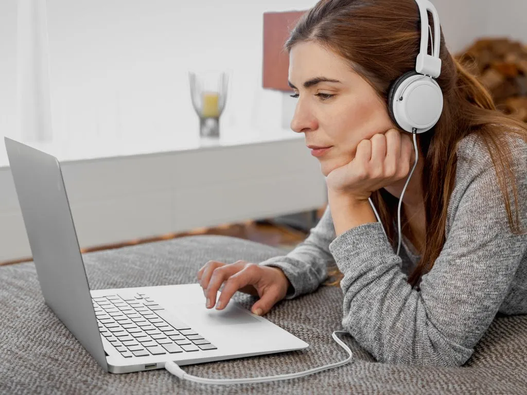 Femme portant un casque audio, concentrée sur son ordinateur portable. Illustration de l’effet de la musique sur la concentration et la productivité, particulièrement utile pour les profils neuroatypiques (TDAH, HPI, autisme)