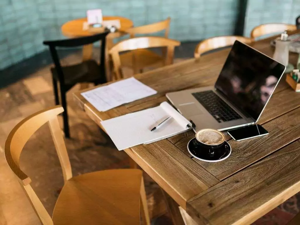 Bureau avec ordinateur portable, carnet et café, illustrant le travail sur un planning éditorial.
