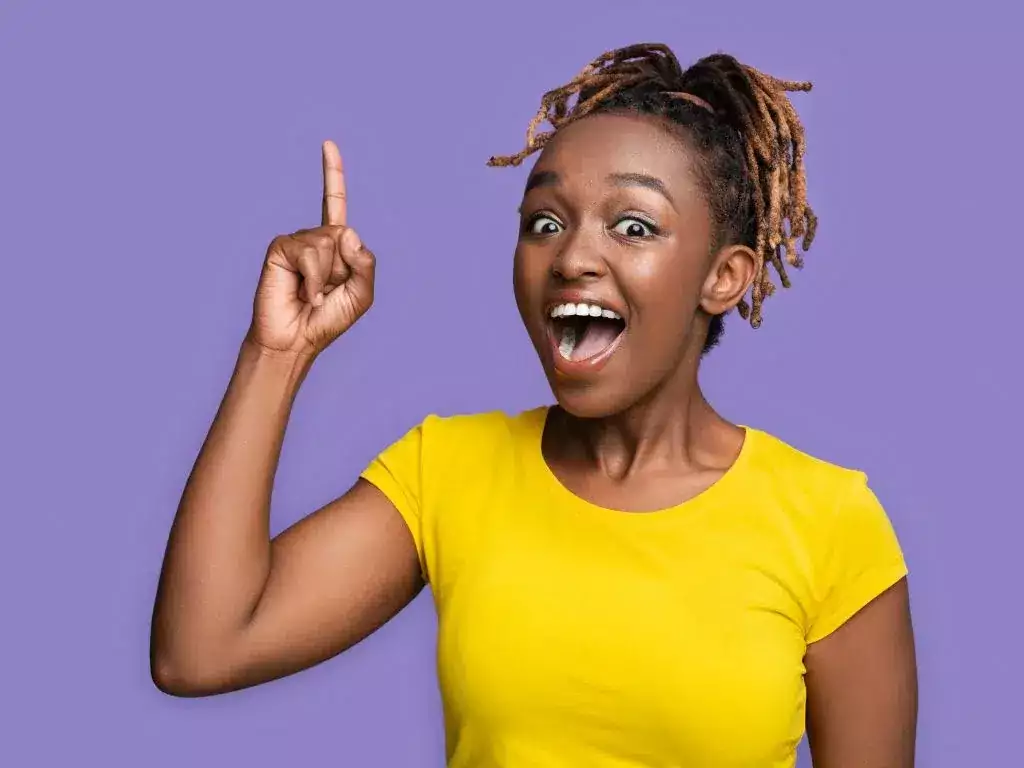 Femme arborant un grand sourire et levant le doigt pour montrer qu'elle a trouvé une idée pour son article de blog