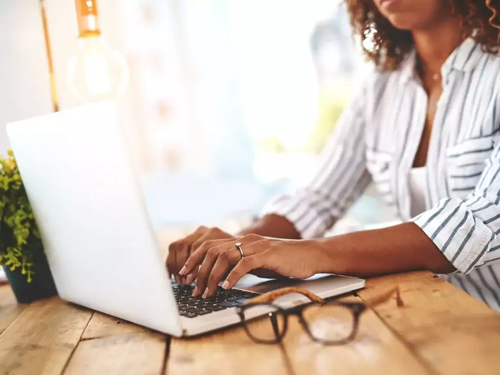Femme entrepreneure travaillant sur son ordinateur à la mise en place d'un blog pour son activité, grâce à WordPress.