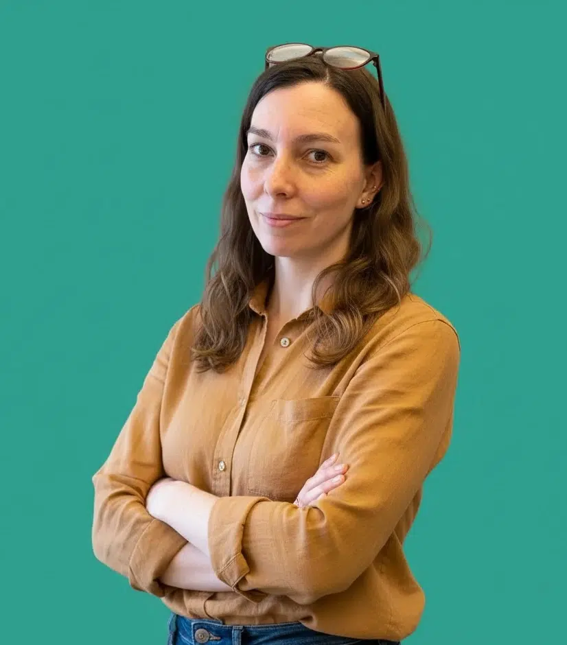 Portrait de 3/4 de Dorothée Berthon, coach SEO, bras croisés et souriante, sur fond vert.